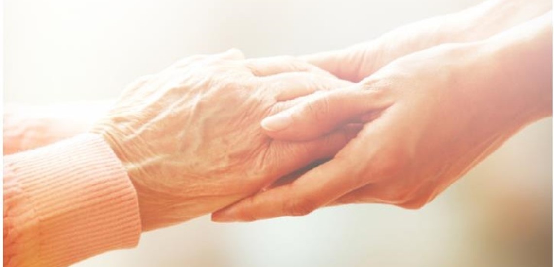 Young person's hands touching an old person's hands